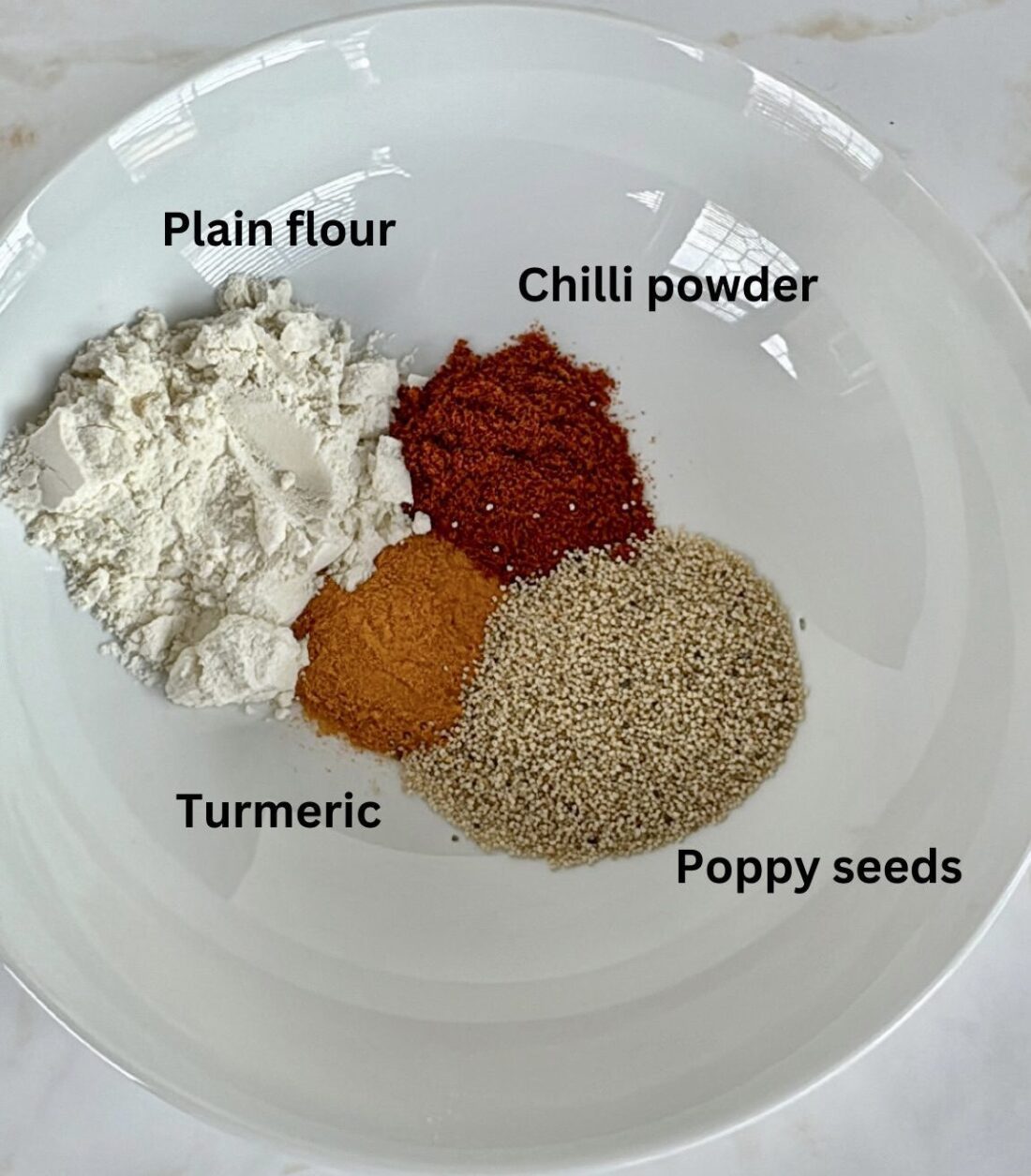 Begun Bhaja Ingredients in a bowl: flour, poppy seeds, turmeric, chilli powder