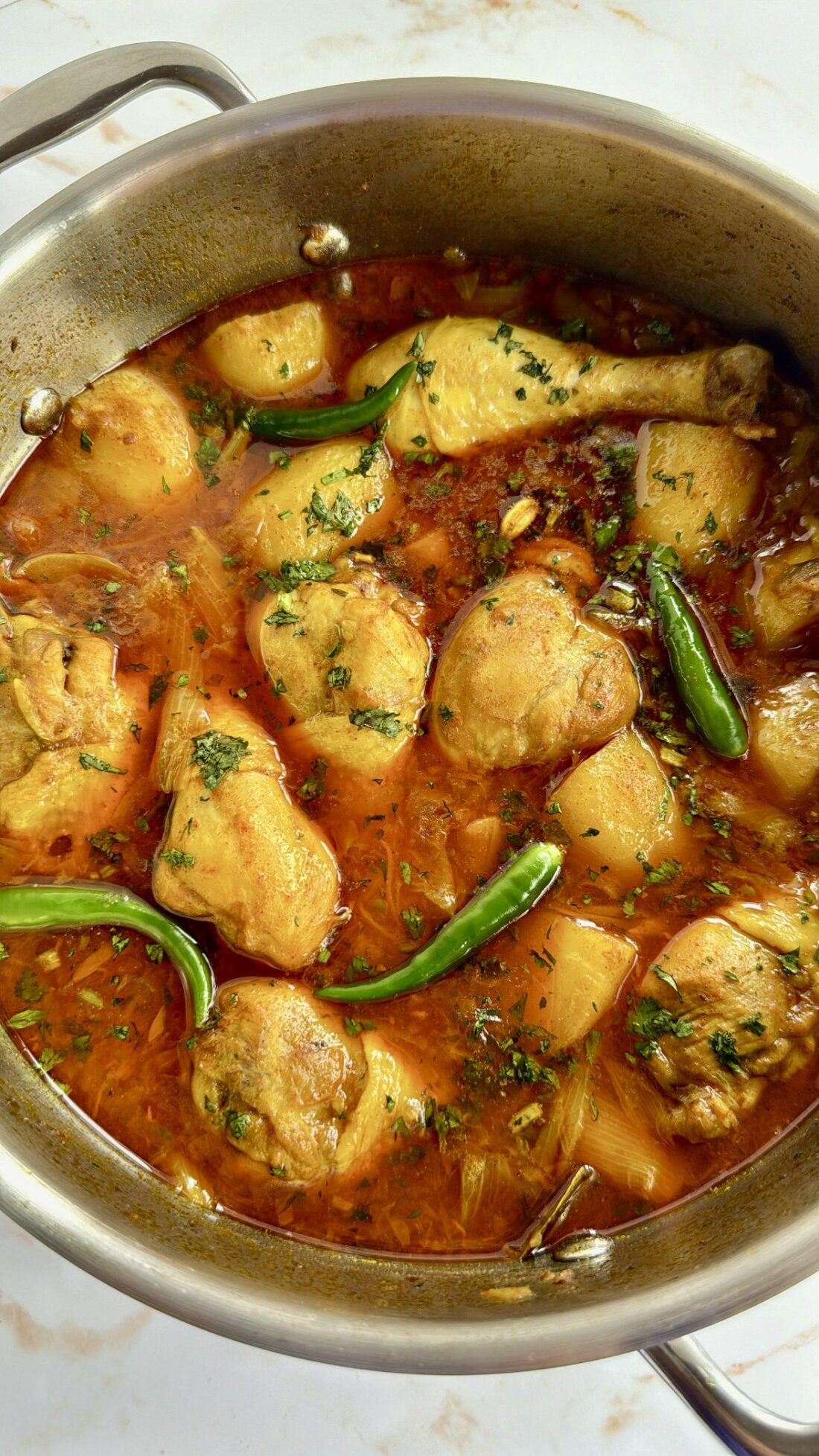 Chicken curry with potatoes and green chillis in a saucepan