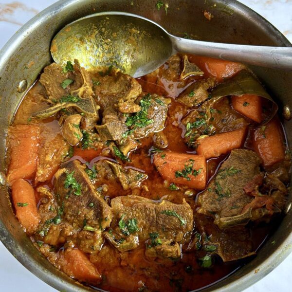 Lamb chops curry in a saucepan with carrots and a spoon