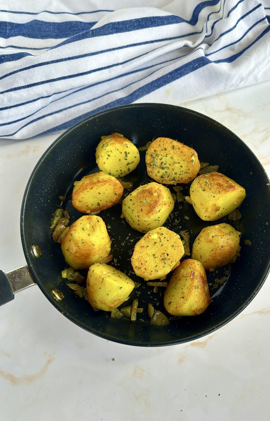 Yellow potatoes in a fry pan, garnished with coriander