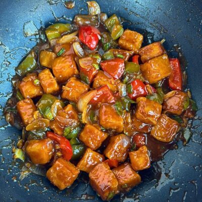 Chilli Paneer coated in sauce in a wok