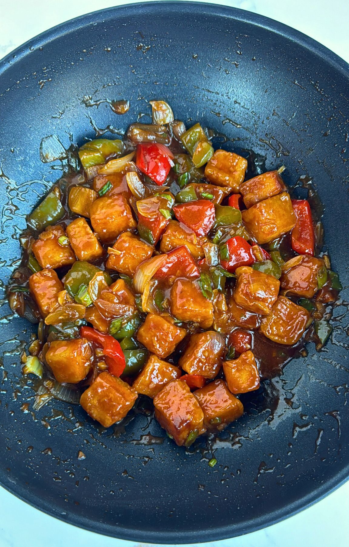 Chilli Paneer coated in sauce in a wok