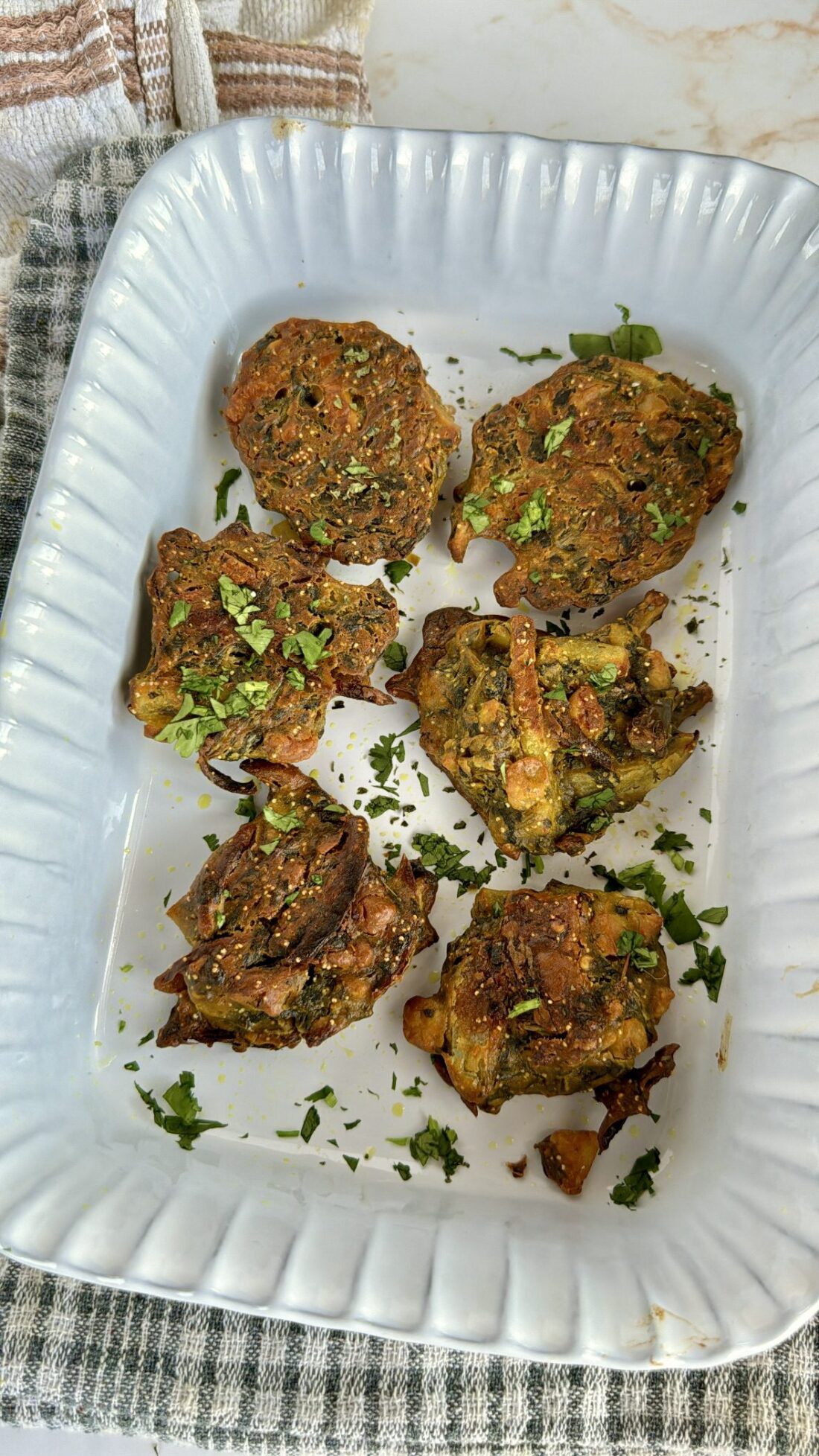 Cooked pakora balls in baking dish garnished with coriander