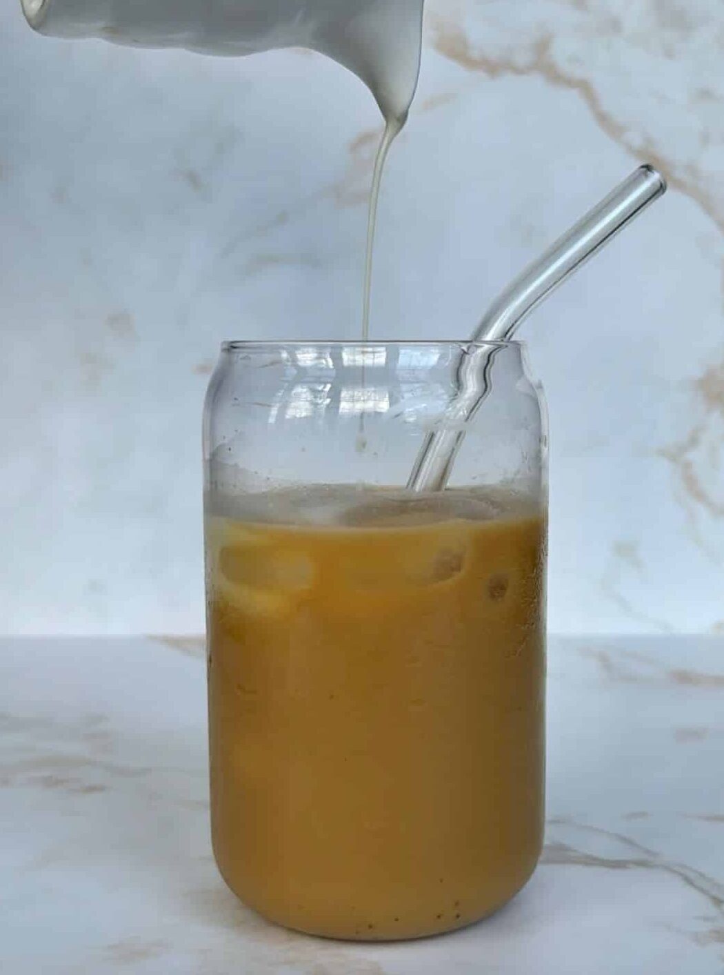 iced chai with milk being poured in