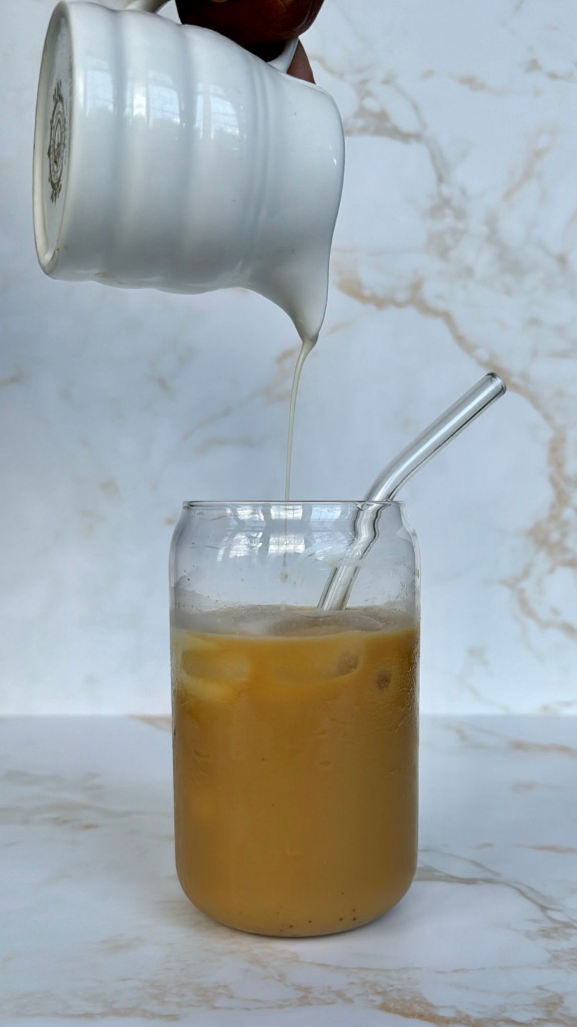 iced chai with milk being poured in