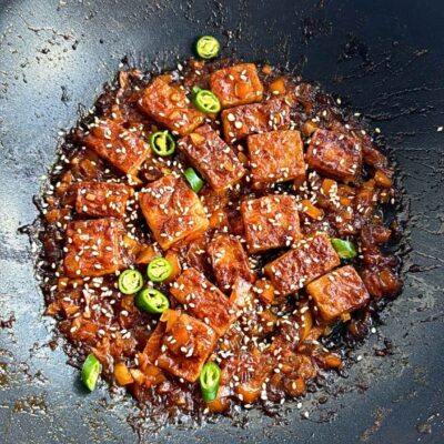 Tofu covered in spicy sauce in a wok