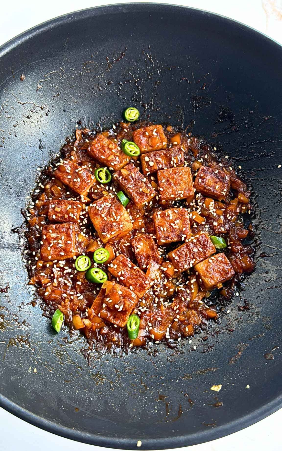 Tofu covered in spicy sauce in a wok