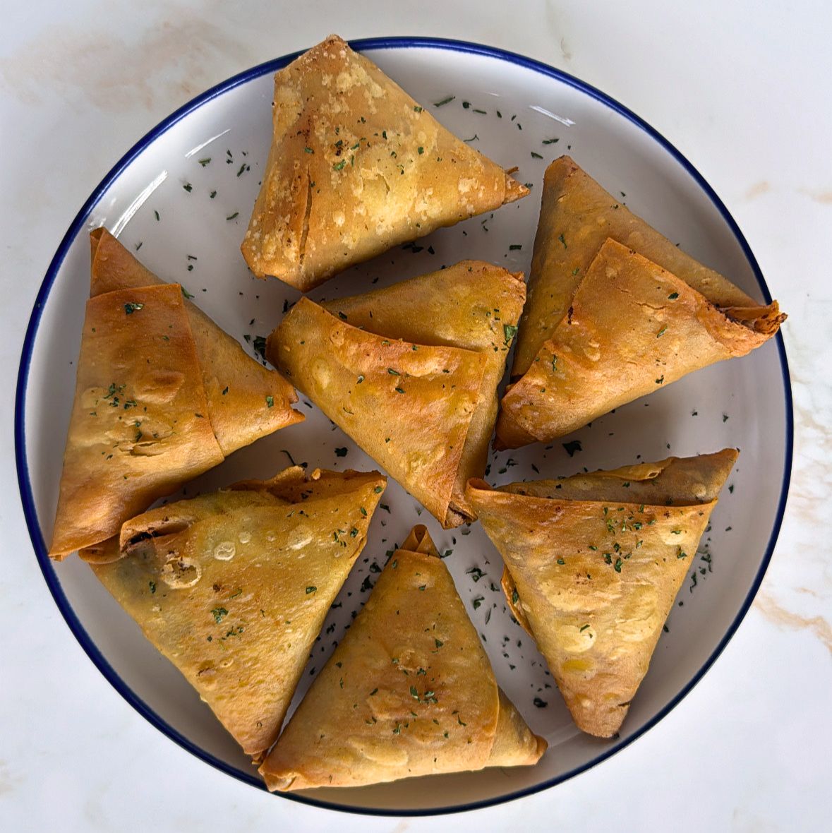 lamb samosas on white plate garnished with coriander