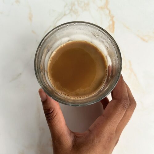 masala chai in glass and hand holding it