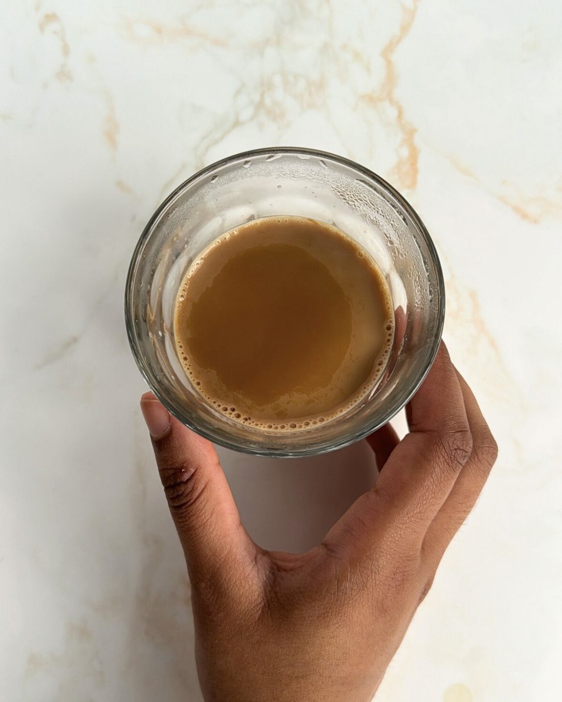 masala chai in glass and hand holding it