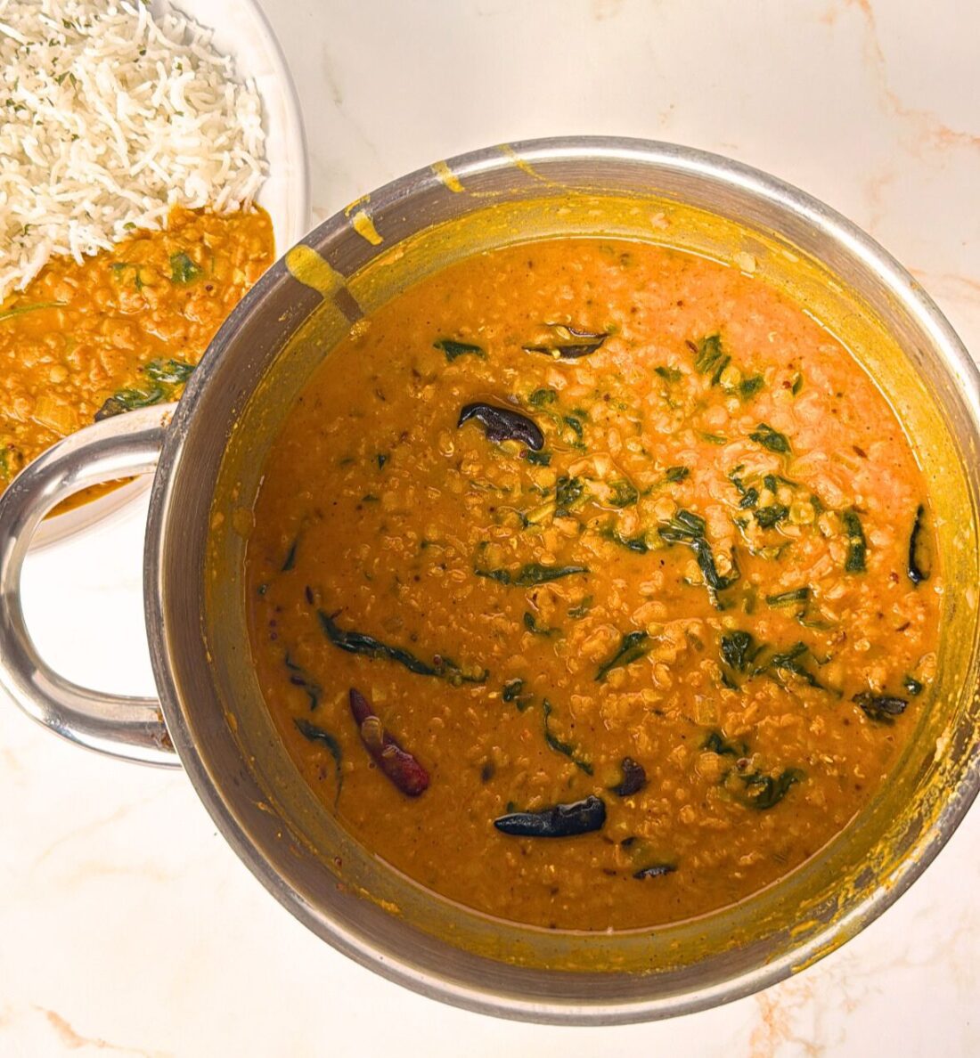 dahl in steel saucepan and rice bowl on the side with dahl