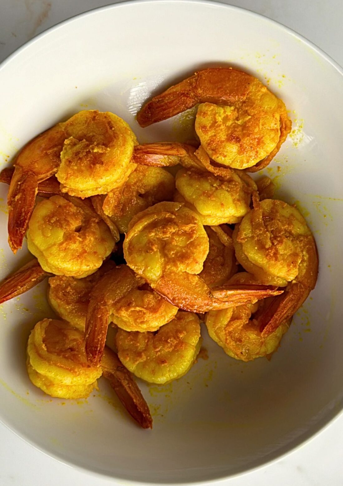 prawns in a bowl, they are golden and yellow as they were fried in turmeric and salt.