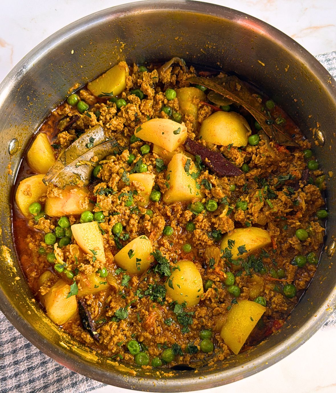 potatoes, spiced meat and peas in a pan