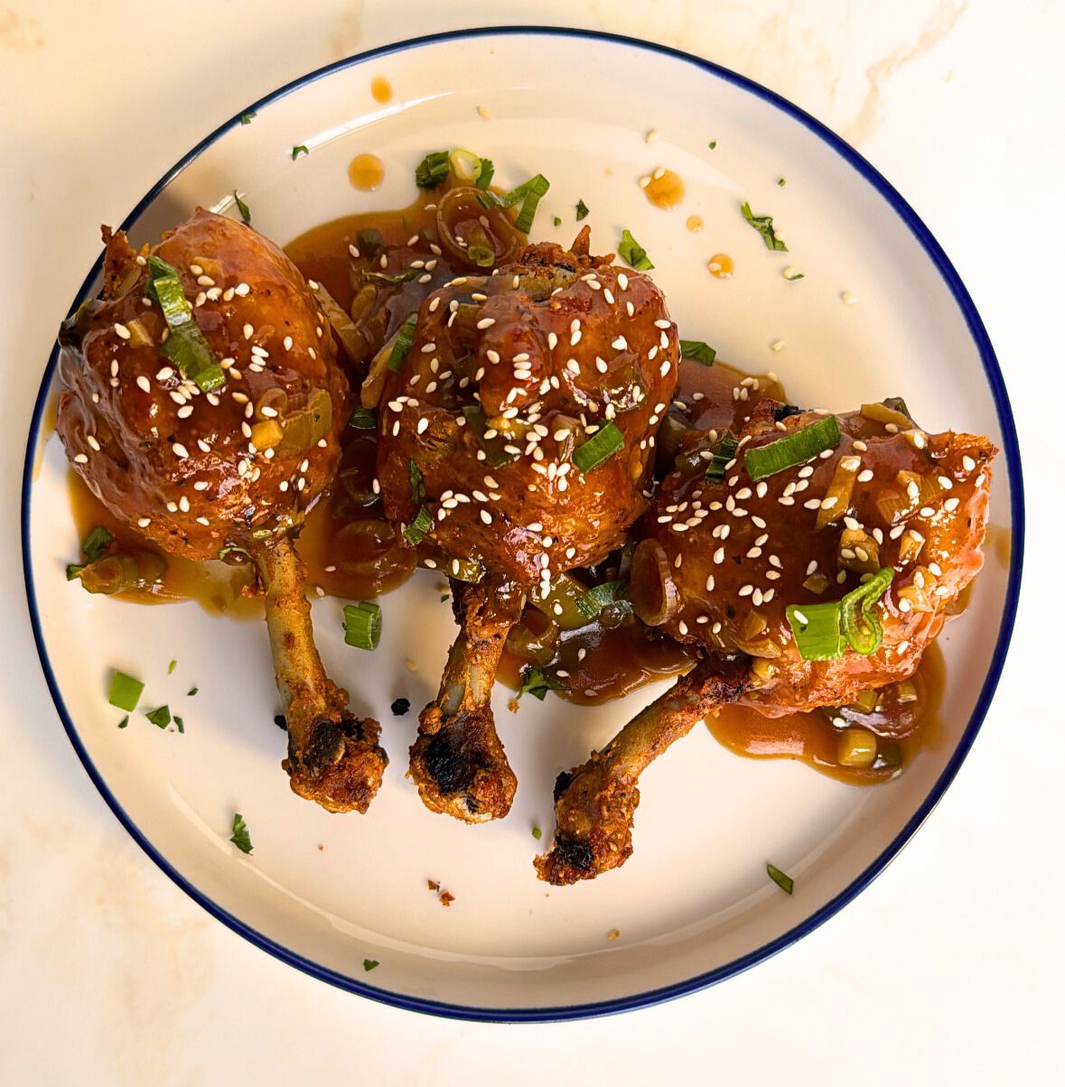 drums of heaven coated in gravy sauce garnished with sesame seeds and spring onions