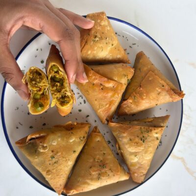 lamb samosas with hands showing filling with peas