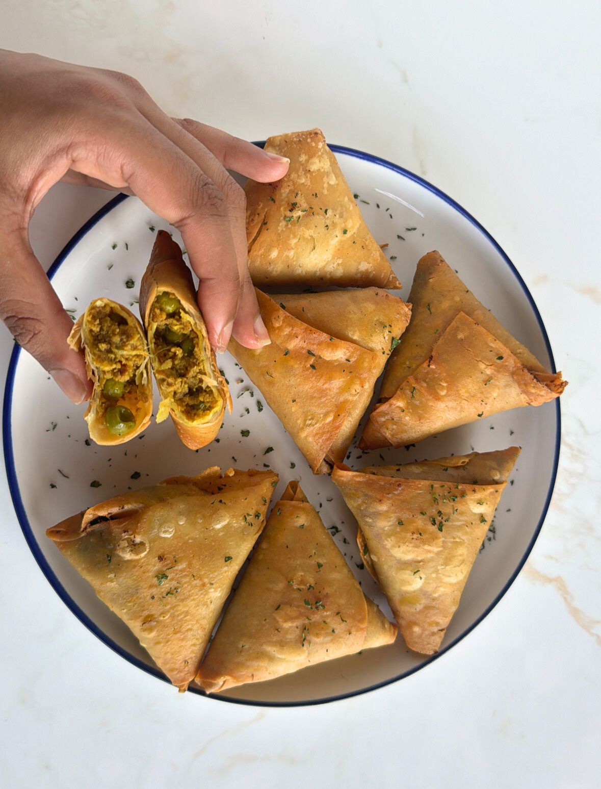 lamb samosas with hands showing filling with peas