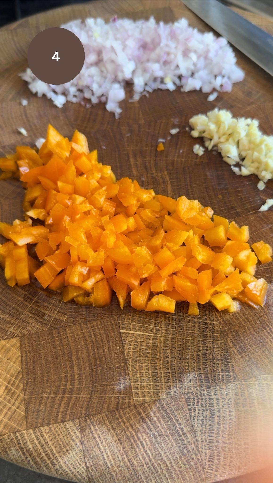 chopped onions, chopped garlic and orange pepper on a chopping board