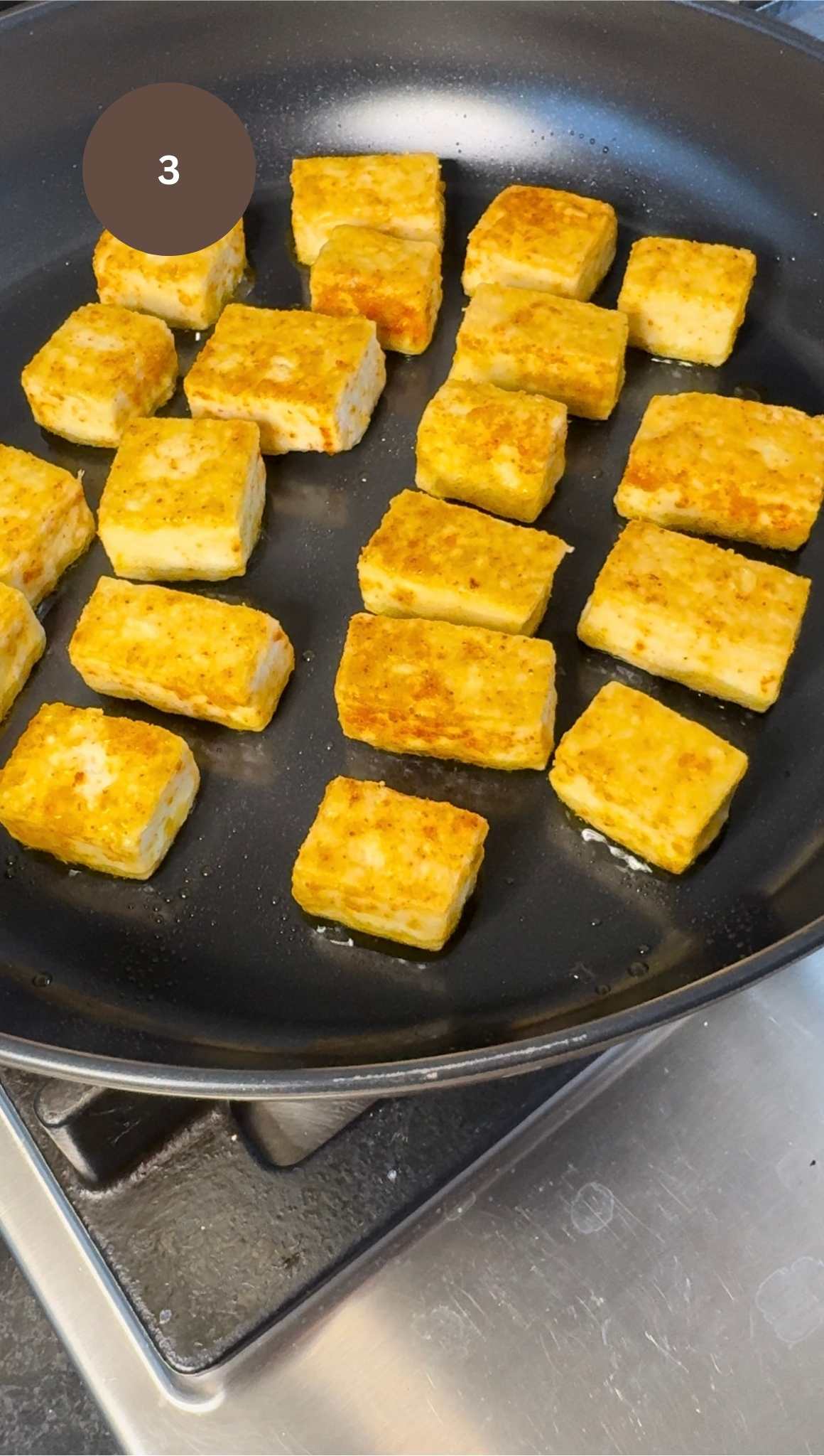 chunks of tofu in fry pan, fried with a golden crispy outer layer