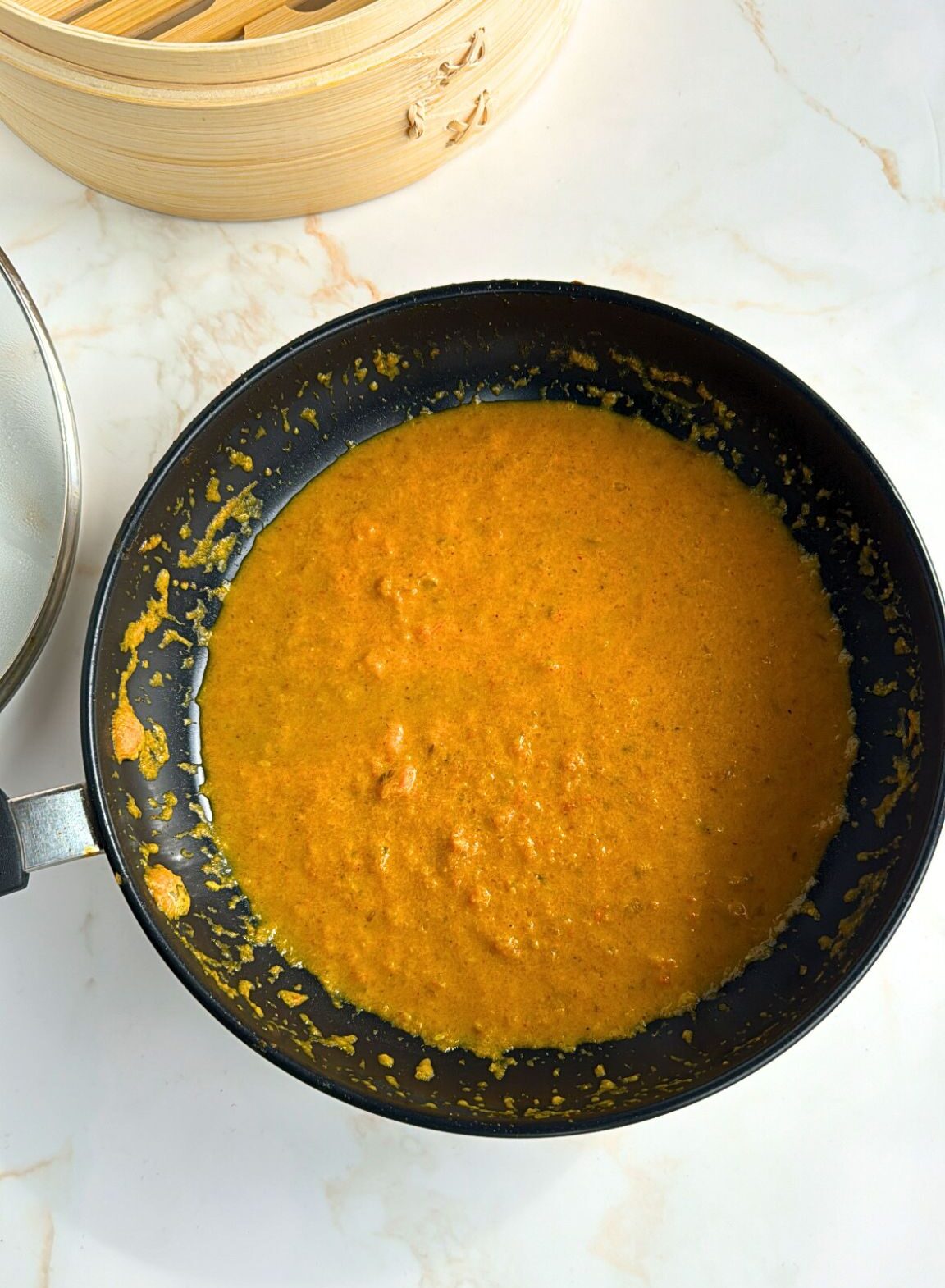 tomato achar sauce in fry pan with steamer in corner of photo