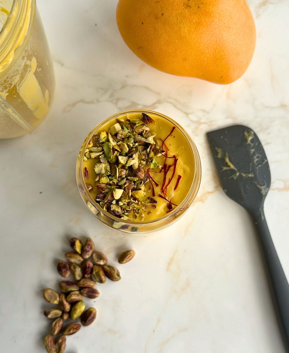 Mango lassi in cup with ingredients scattered around it