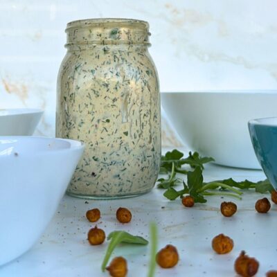 salad dressing in bell jar and chickpeas and rocket scattered around it