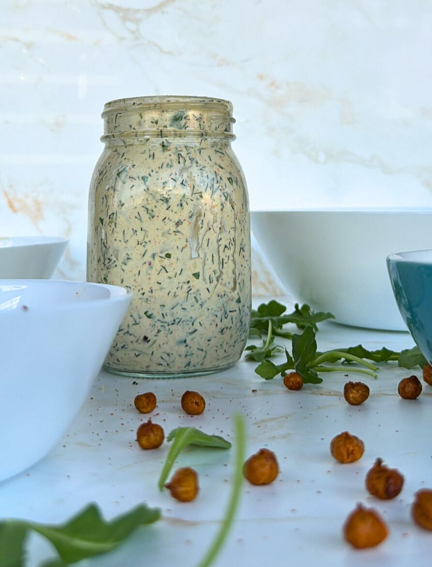 salad dressing in bell jar and chickpeas and rocket scattered around it